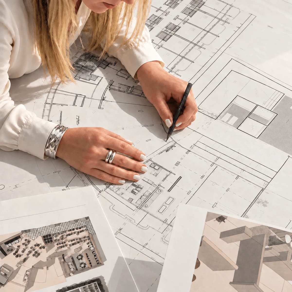 A designer annotating architectural plans beside interior design references