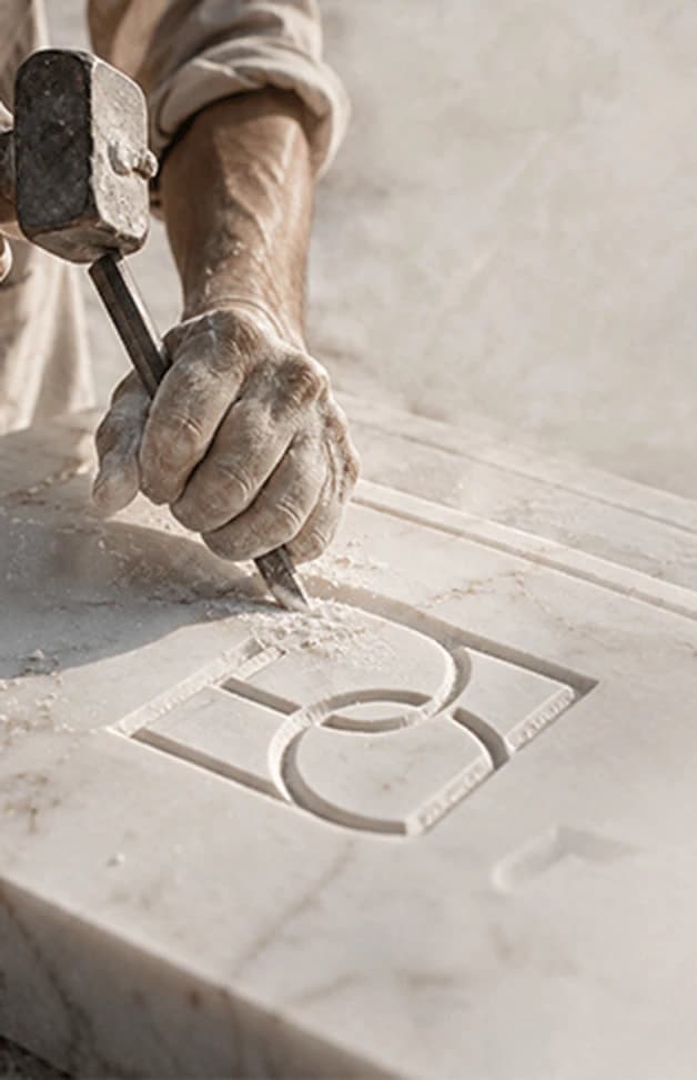 Hands carving the Deboss emblem into stone
